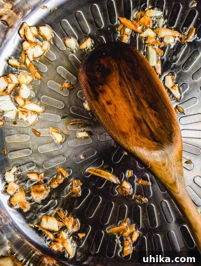 Sautéing Garlic for Pizza Sauce Chopped garlic cloves sizzling in olive oil in a pan.