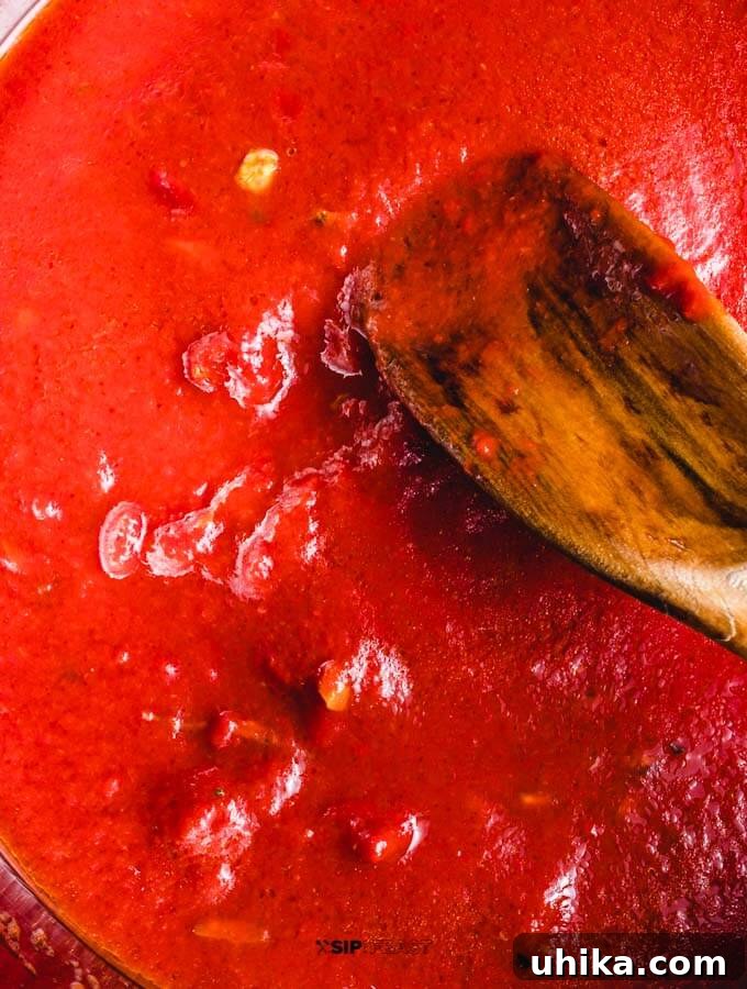 Adding Tomato Paste to Garlic Tomato paste being added to the pan with sautéed garlic.
