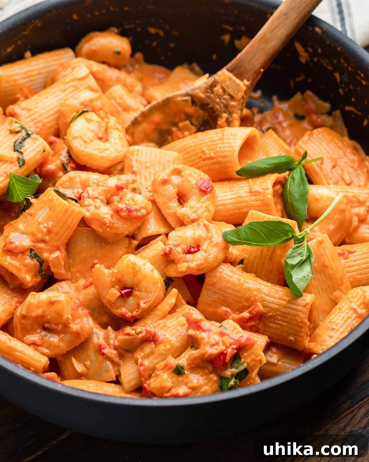 A black pan brimming with Shrimp alla Vodka, showcasing the creamy pink sauce, pasta, and perfectly cooked shrimp, garnished with fresh basil.