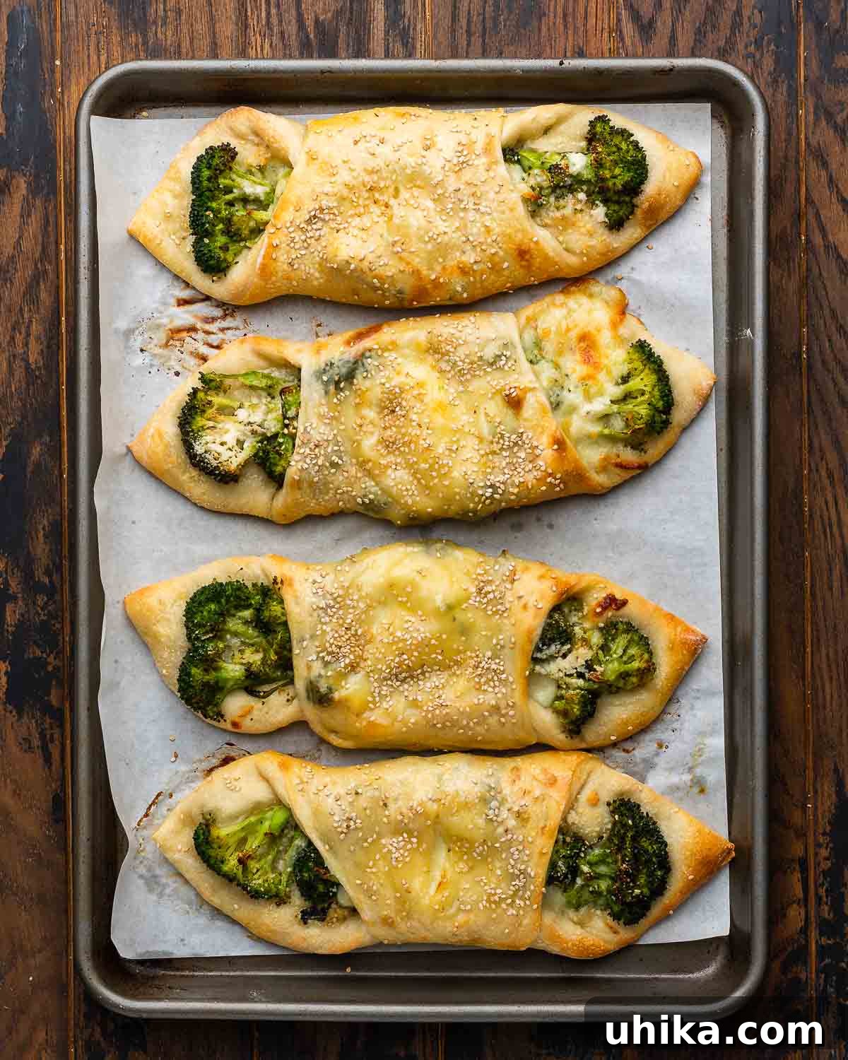 Broccoli Pinwheels 8 Overhead shot of freshly baked Italian broccoli rolls arranged neatly in a sheet pan, showcasing their golden crust and sesame seed topping.