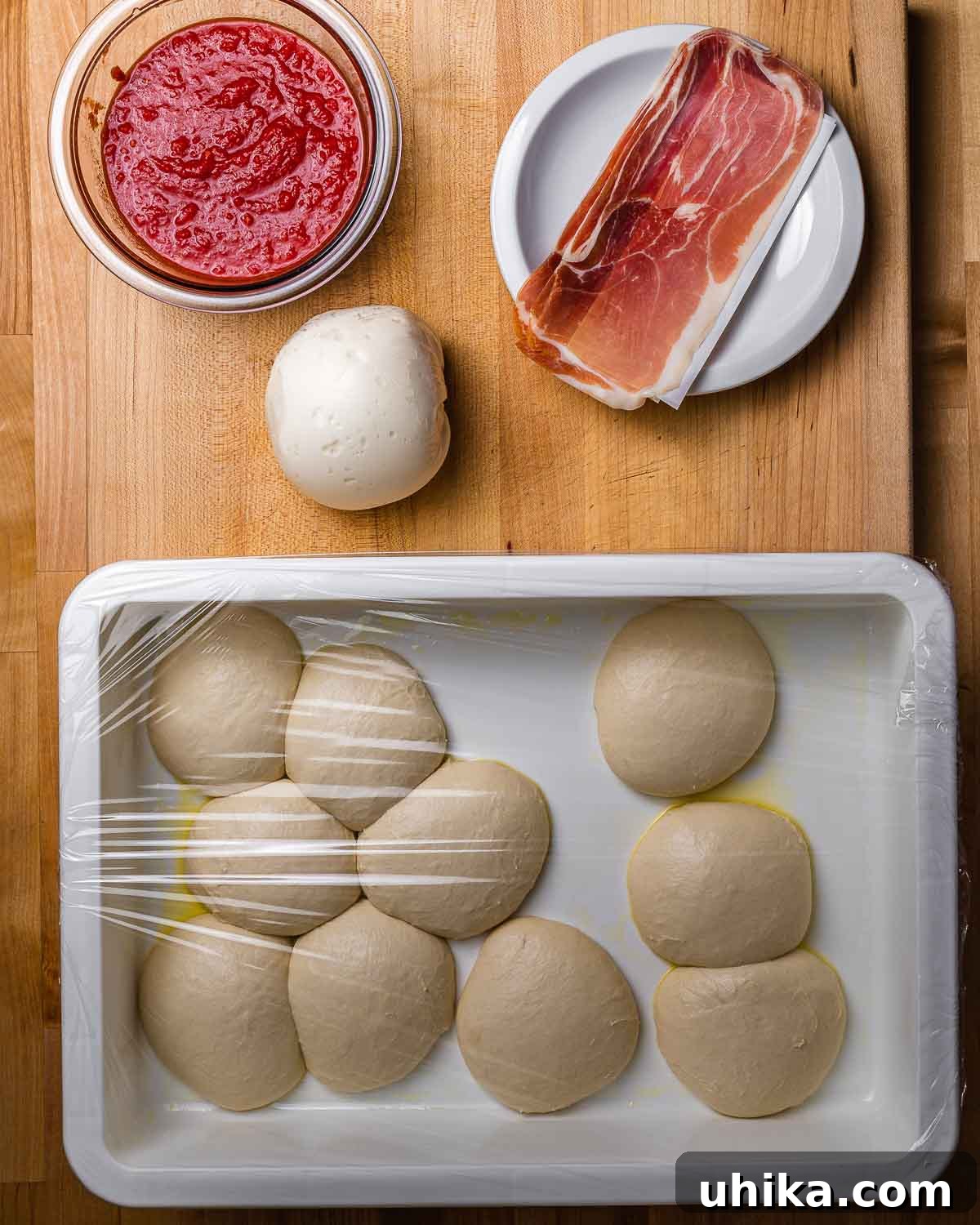 Crispy Italian Panzerotti 3 A collage of ingredients for panzerotti, including a bowl of crushed tomatoes, a fresh mozzarella ball, slices of prosciutto, and ten small, perfectly portioned dough balls.