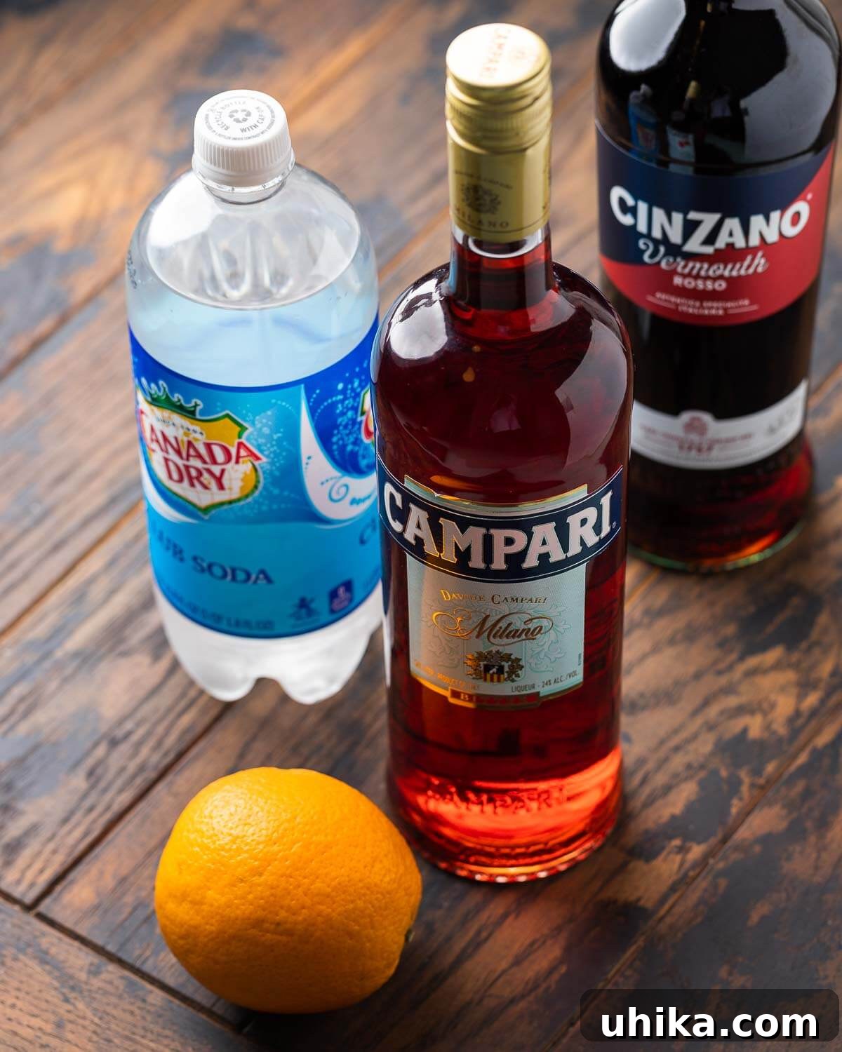 Ingredients shown: club soda, sweet vermouth, campari, and an orange.