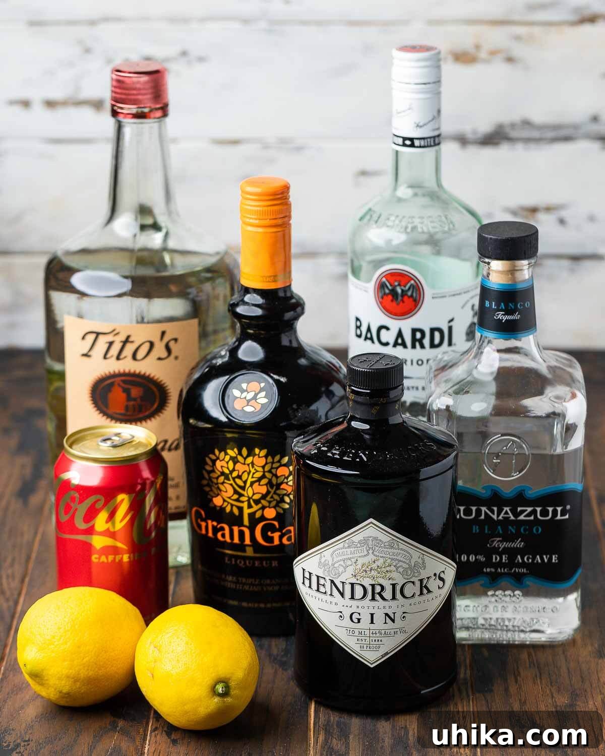 Long Island Iced Tea 3 Ingredients for Long Island Iced Tea shown: vodka, orange liqueur (Gran Gala), cola, lemons, gin, white rum, and blanco tequila.