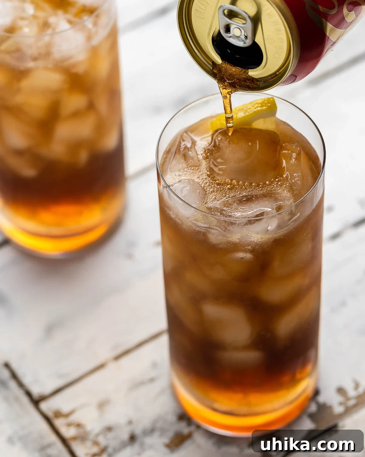 Long Island Iced Tea 4 Hands pouring Coca-Cola into a highball glass containing a Long Island Iced Tea mix.