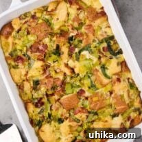 A white oblong casserole with handles filled with freshly baked savory bread pudding with bacon and leeks, a delicious brunch or side dish.