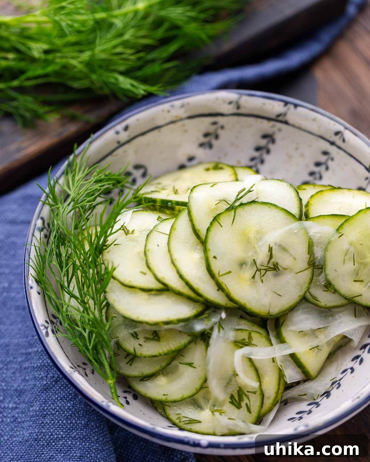 Crisp Cucumber Cool-down 7 Closeup shot of cucumber salad in a blue and white bowl, with a matching blue napkin in the background, highlighting its fresh appeal.