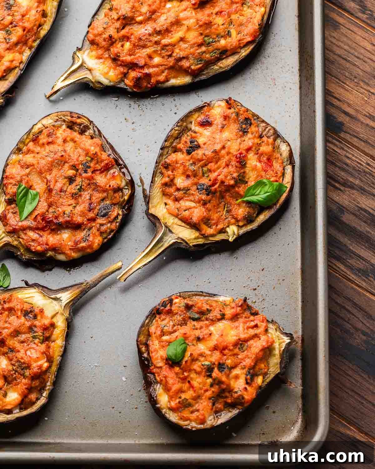 Hearty Stuffed Eggplant Boats 2 Overhead shot of baking tray with stuffed eggplant, golden brown and garnished with fresh herbs.