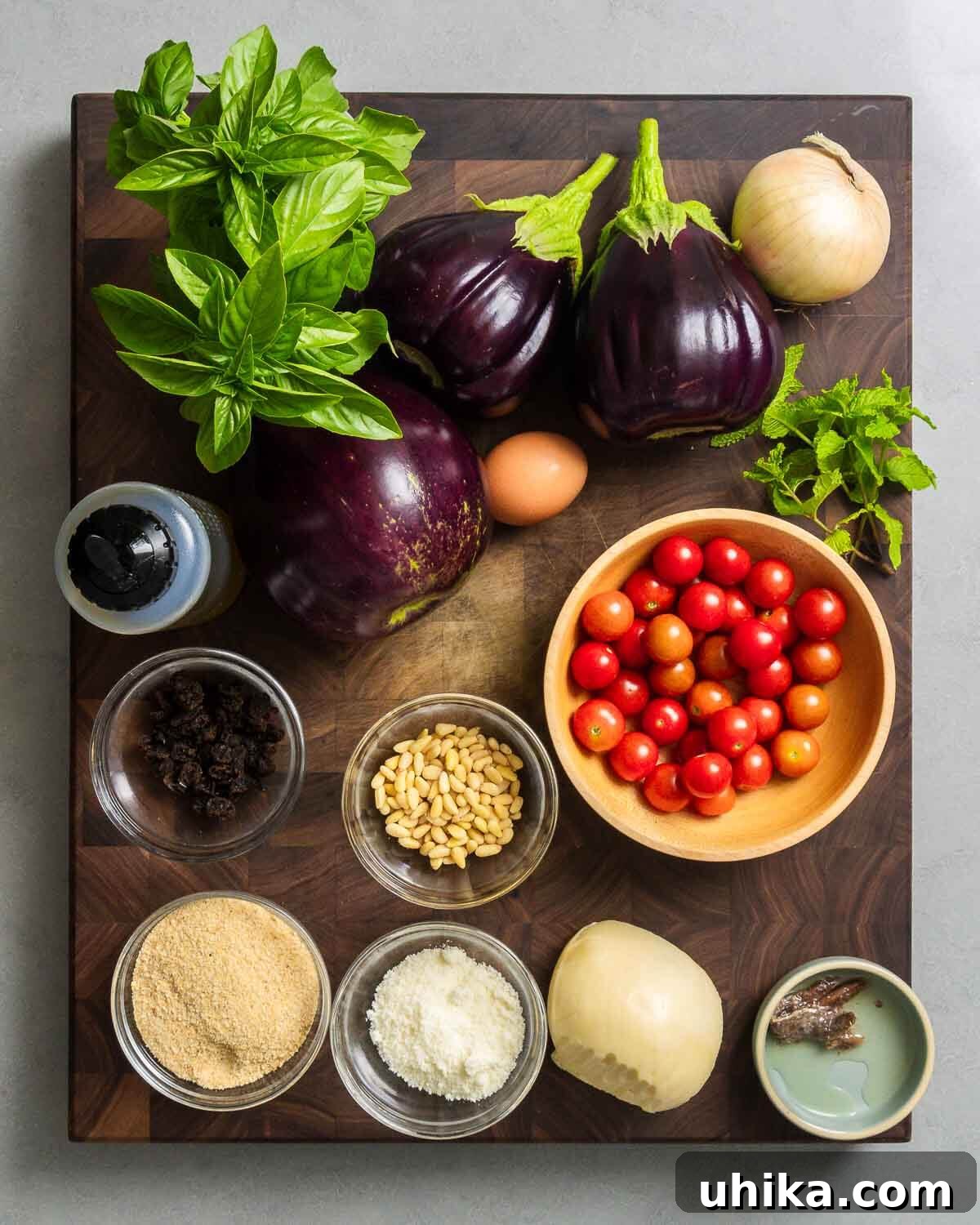 Hearty Stuffed Eggplant Boats 3 Ingredients for Sicilian stuffed eggplant: basil, mint, eggplant, onion, garlic, egg, olive oil, raisins, pine nuts, cherry tomatoes, breadcrumbs, Pecorino, Scamorza, and anchovies.