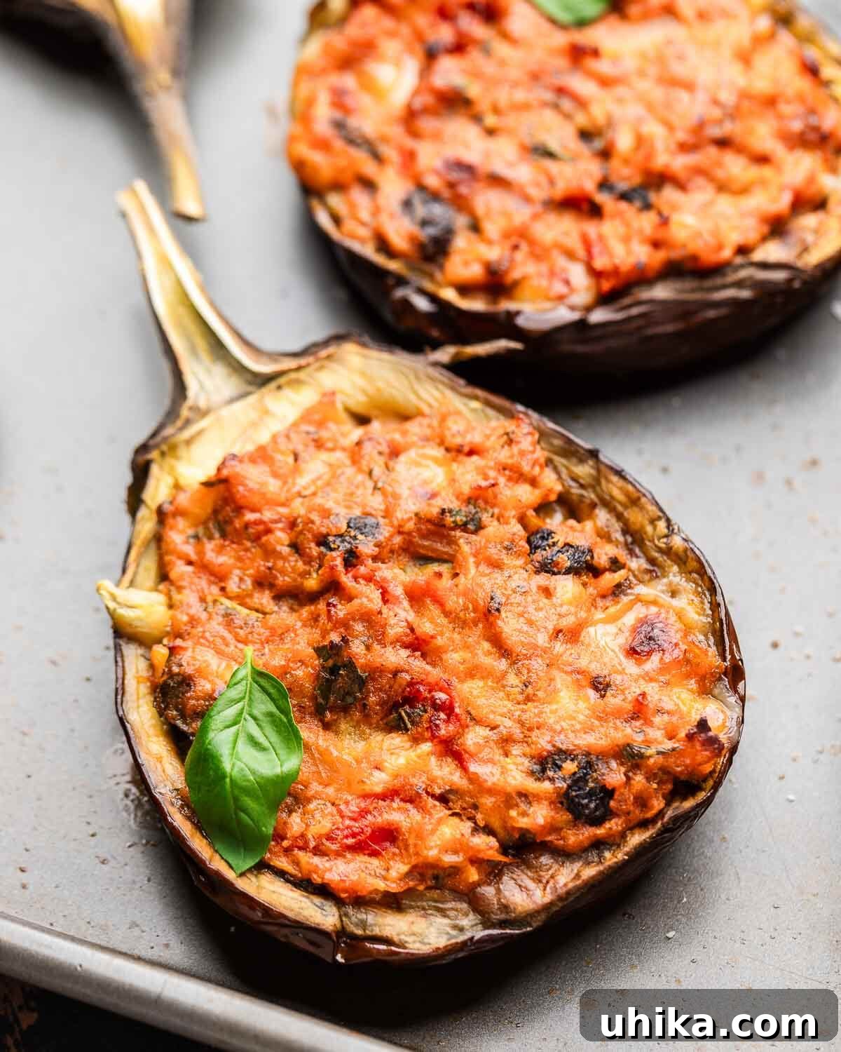 Hearty Stuffed Eggplant Boats 8 Closeup shot of a single perfectly baked stuffed eggplant on a baking sheet, garnished.