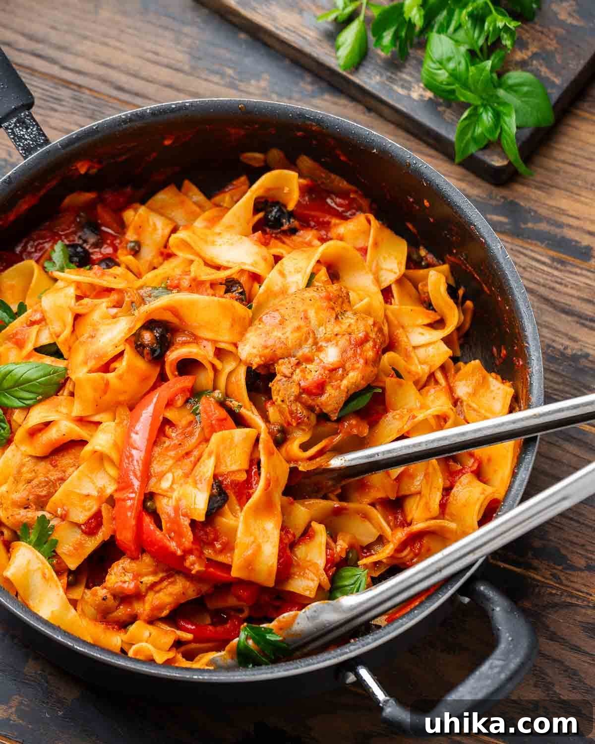 Rustic Chicken Cacciatore Pasta 8 Large pan with chicken cacciatore pasta with tongs and board with basil and parsley.