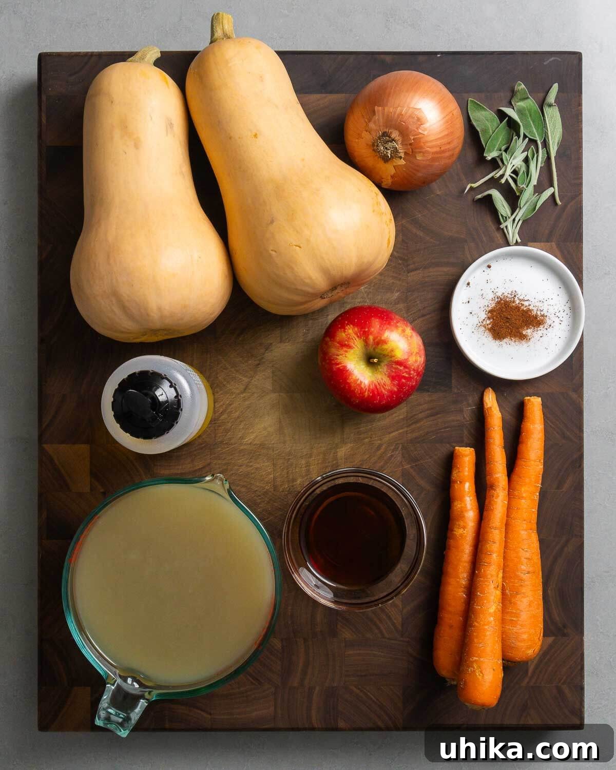 Silken Roasted Butternut Bliss 3 A vibrant display of fresh ingredients for roasted butternut squash soup, including squash, onion, sage, olive oil, apple, nutmeg, vegetable stock, maple syrup, and carrots.