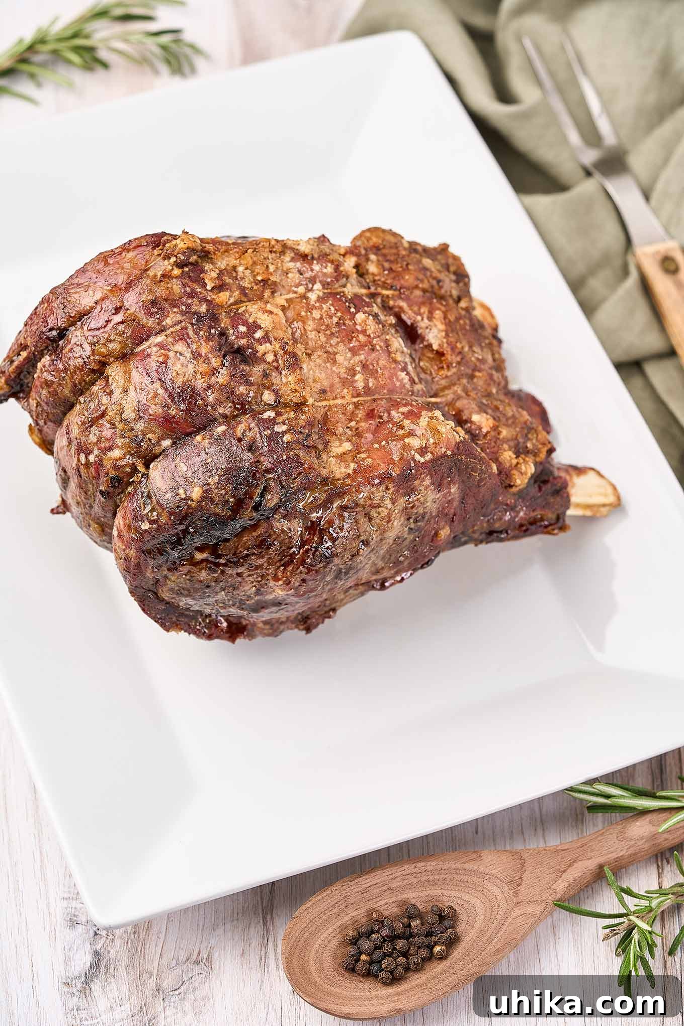 Mastering the Perfect Prime Rib 5 A beautifully cooked prime rib roast resting on a pristine white serving platter, having just been removed from the oven and waiting to be carved for a special occasion feast.