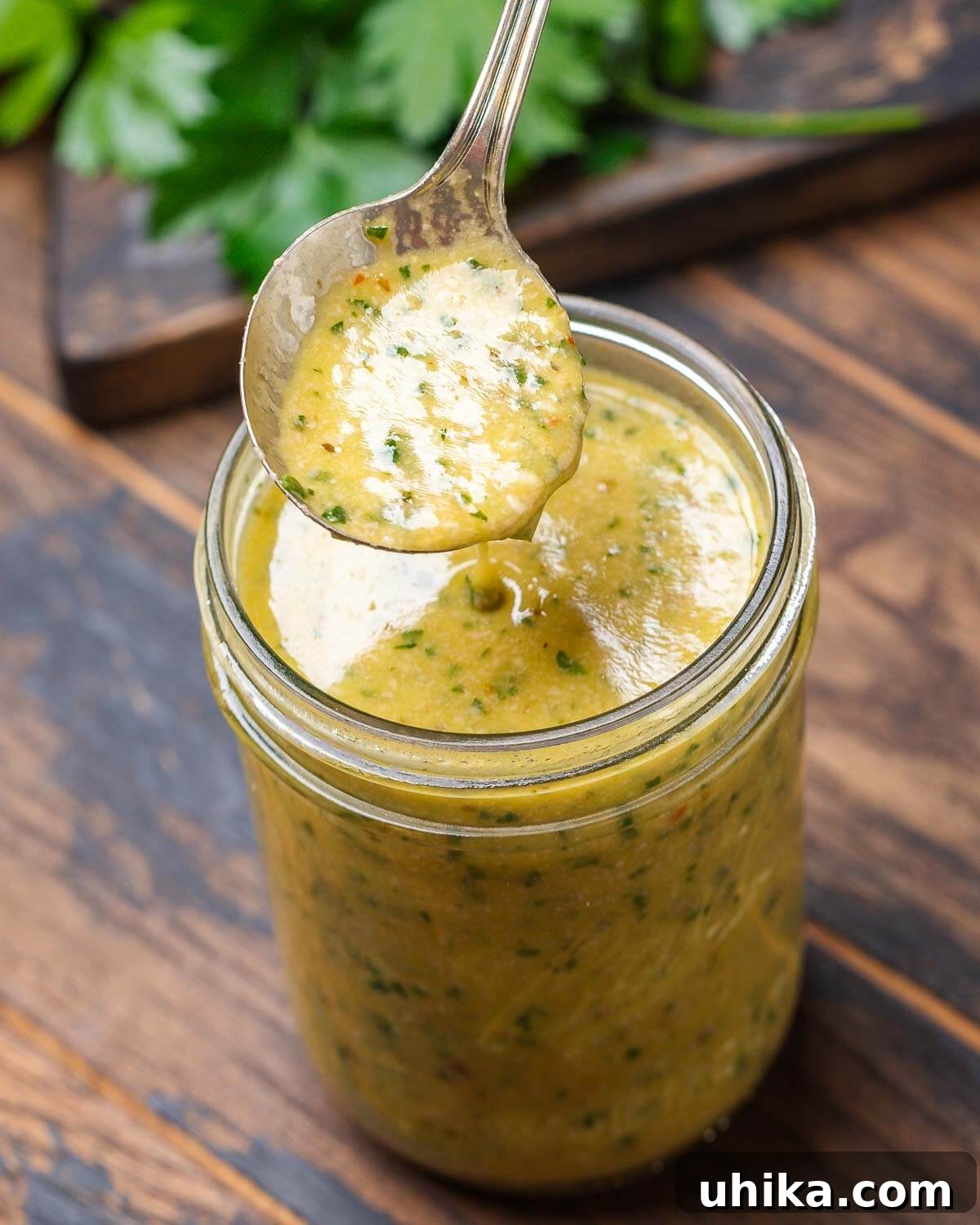 Zesty Italian Vinaigrette 2 Spoon drizzling Italian vinaigrette over mason jar.