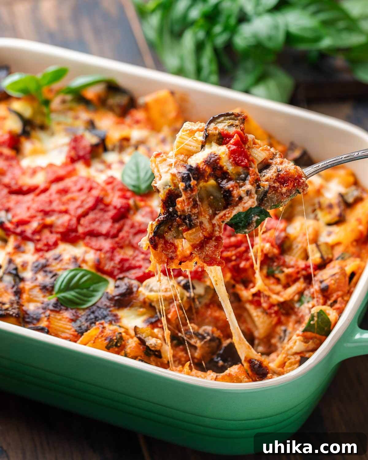 Roasted Eggplant Pasta Bake 9 Serving spoon pulling a scoop of baked eggplant pasta out of the baking dish, showing gooey cheese and tender eggplant.