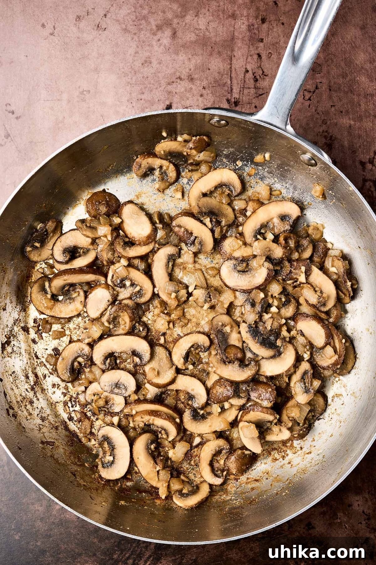Creamy Marsala Chicken Pasta with Burst Tomatoes 4 A frying pan showing beautifully browned mushrooms with garlic and onions, ready for the addition of Marsala wine to make a sauce.