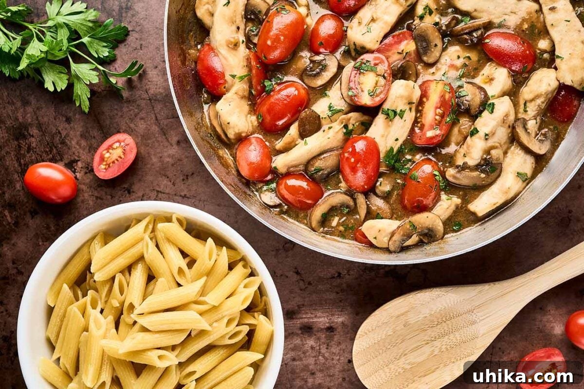 Creamy Marsala Chicken Pasta with Burst Tomatoes 6 A frying pan filled with chicken Marsala with fresh tomatoes next to a bowl of cooked penne pasta, ready to be combined to finish the dish.