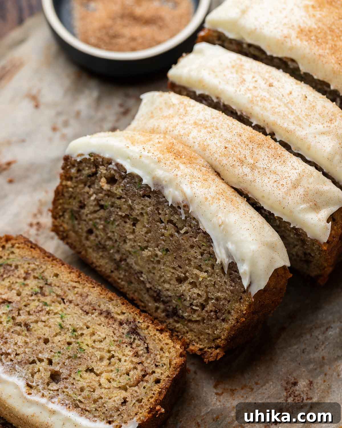 Moist Zucchini Loaf 2 Closeup shot of 4 slices of zucchini bread with sprinkled cinnamon sugar and cream cheese frosting, showcasing its moist texture and delicious toppings.