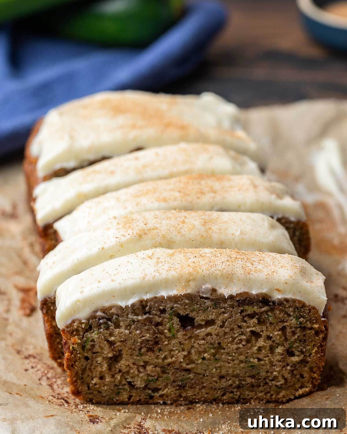 Moist Zucchini Loaf 8 Closeup shot of a perfectly cut slice of zucchini bread with a thick layer of cream cheese frosting, highlighting the cinnamon sugar swirls within.