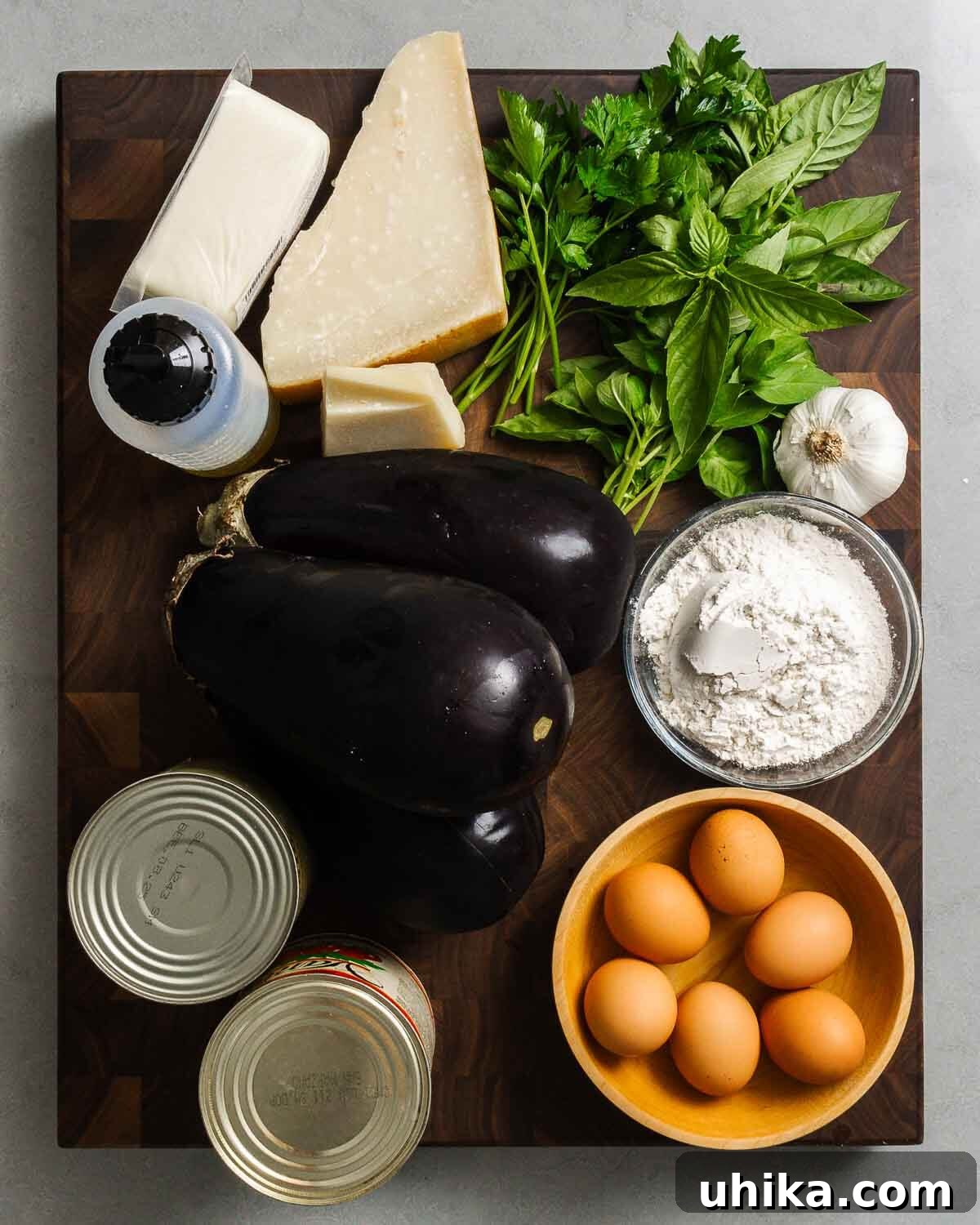 Golden Baked Eggplant Parmesan 3 Ingredients shown: olive oil, mozzarella, parmesan, pecorino, parsley, basil, garlic, eggplants, flour, tomatoes, and eggs.