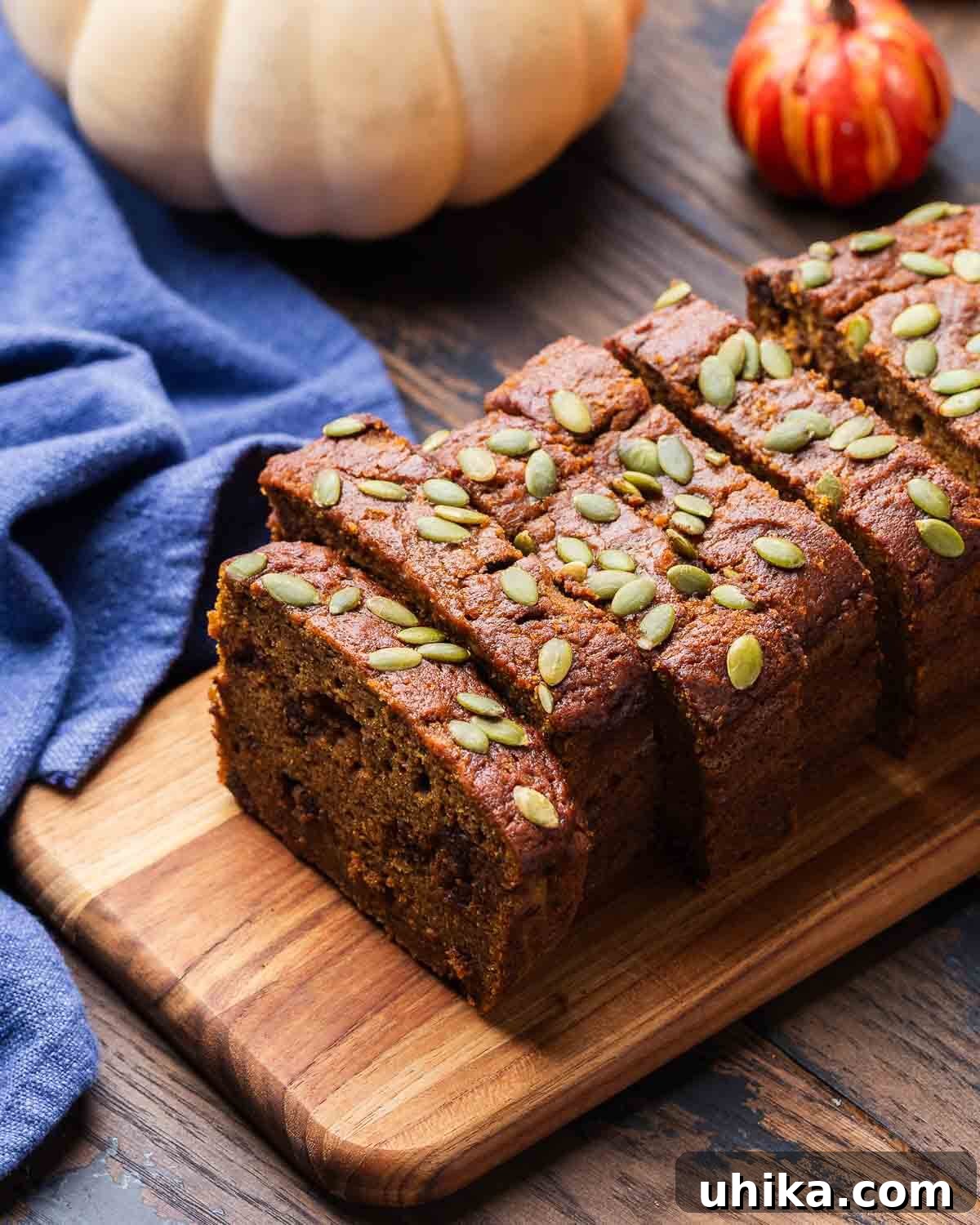 Golden Pumpkin Spice Bread 2 Sliced pumpkin bread on a wood board with white and orange pumpkins in the background. A perfect fall treat for breakfast or dessert.