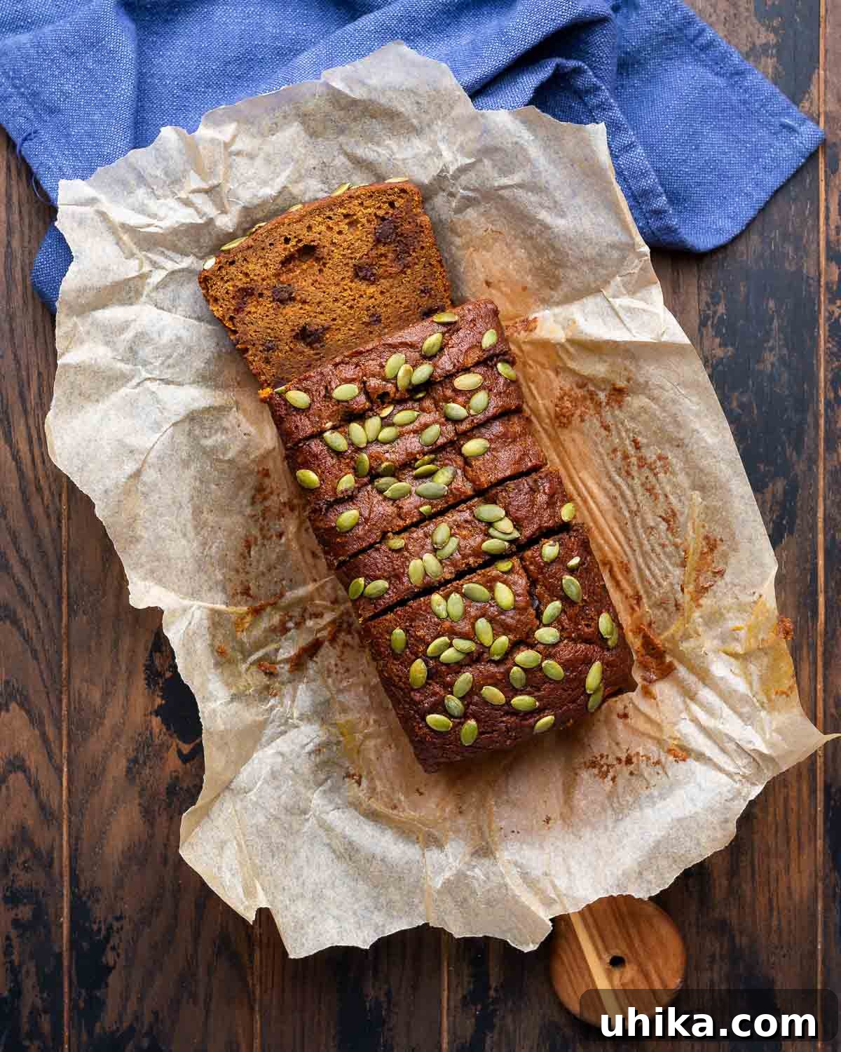 Golden Pumpkin Spice Bread 7 Overhead shot of sliced pumpkin bread topped with pumpkin seeds on top of parchment paper, ready to be served.