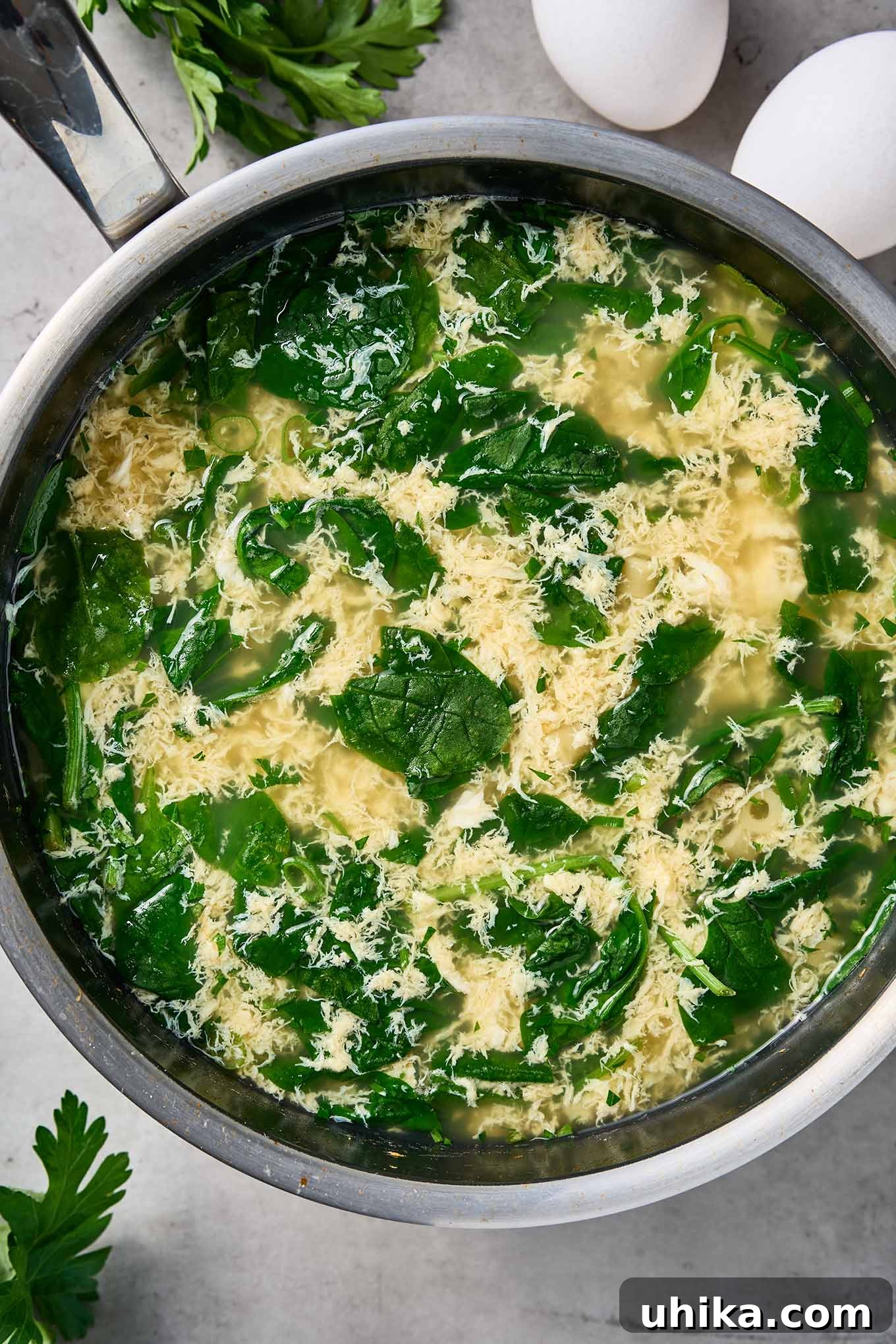 Silken Stracciatella with Fresh Spinach and Tender Pasta 5 Fresh spinach wilting in a pot of stracciatella soup with egg ribbons and broth.