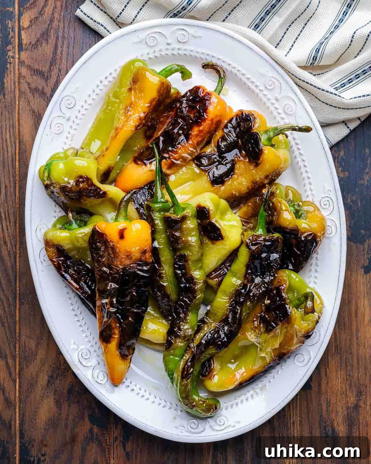 Classic Italian Sautéed Peppers 6 Overhead shot of a white platter with fried Italian frying (Cubanelle) and long hot peppers, garnished.