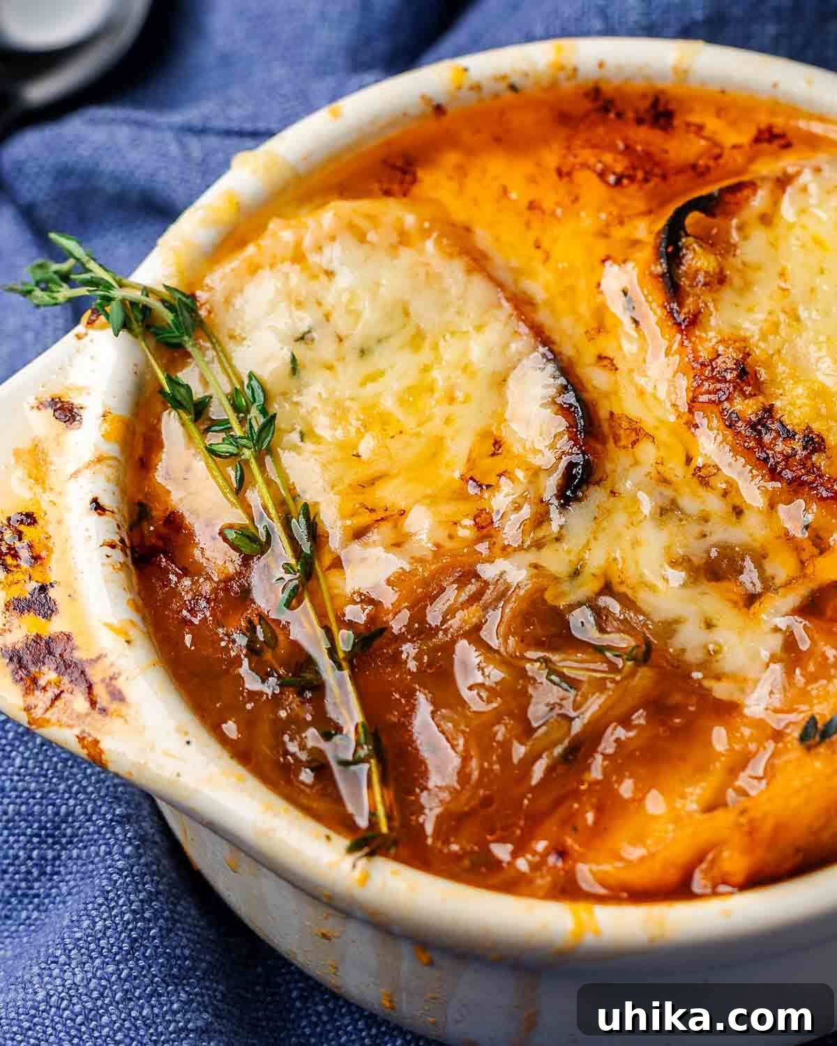 Caramelized Onion Elegance 2 Closeup shot of French onion soup in white bowl, garnished with fresh thyme.