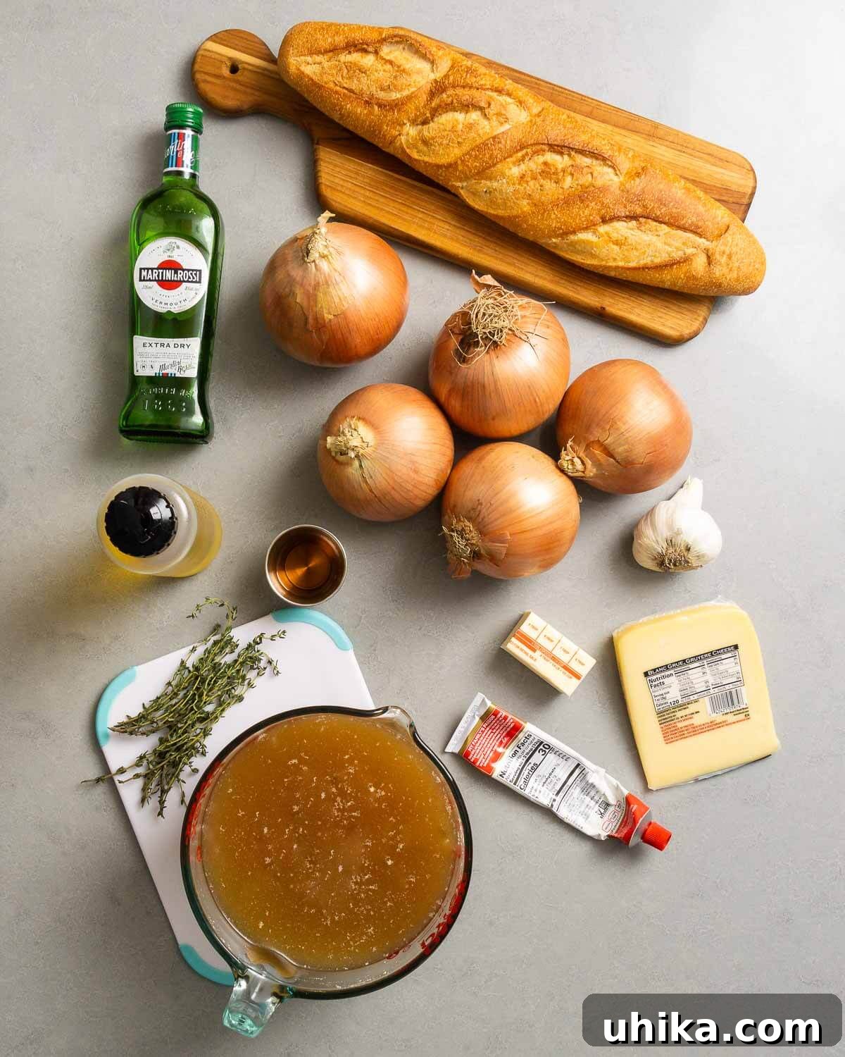 Caramelized Onion Elegance 3 A vibrant flat lay of all ingredients for French onion soup including onions, olive oil, butter, garlic, tomato paste, vermouth, beef stock, fresh thyme, baguette, and Gruyere cheese.