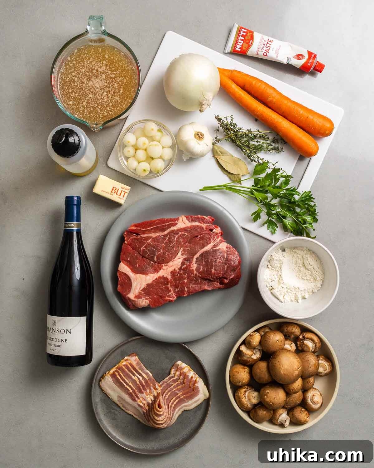 Beef Bourguignon: An Unrivaled Classic Stew 4 Ingredients shown: beef stock, olive oil, butter, pearl onions, garlic, onion, thyme, bay leaves, parsley, carrots, tomato paste, Burgundy wine, beef, bacon, flour, and mushrooms.