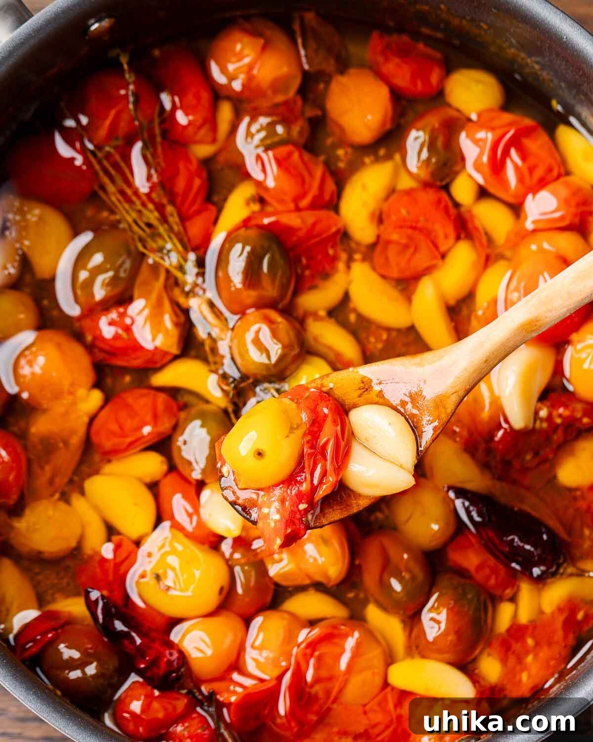 Rich Roasted Tomato Jewels 6 An overhead shot of a spoon holding a generous portion of tomato garlic confit over the pan, highlighting its vibrant colors and rich texture.