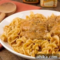 Creamy chicken paprikash featuring tender chicken thighs in a smooth, paprika-infused sauce, nestled on a bed of egg noodles.