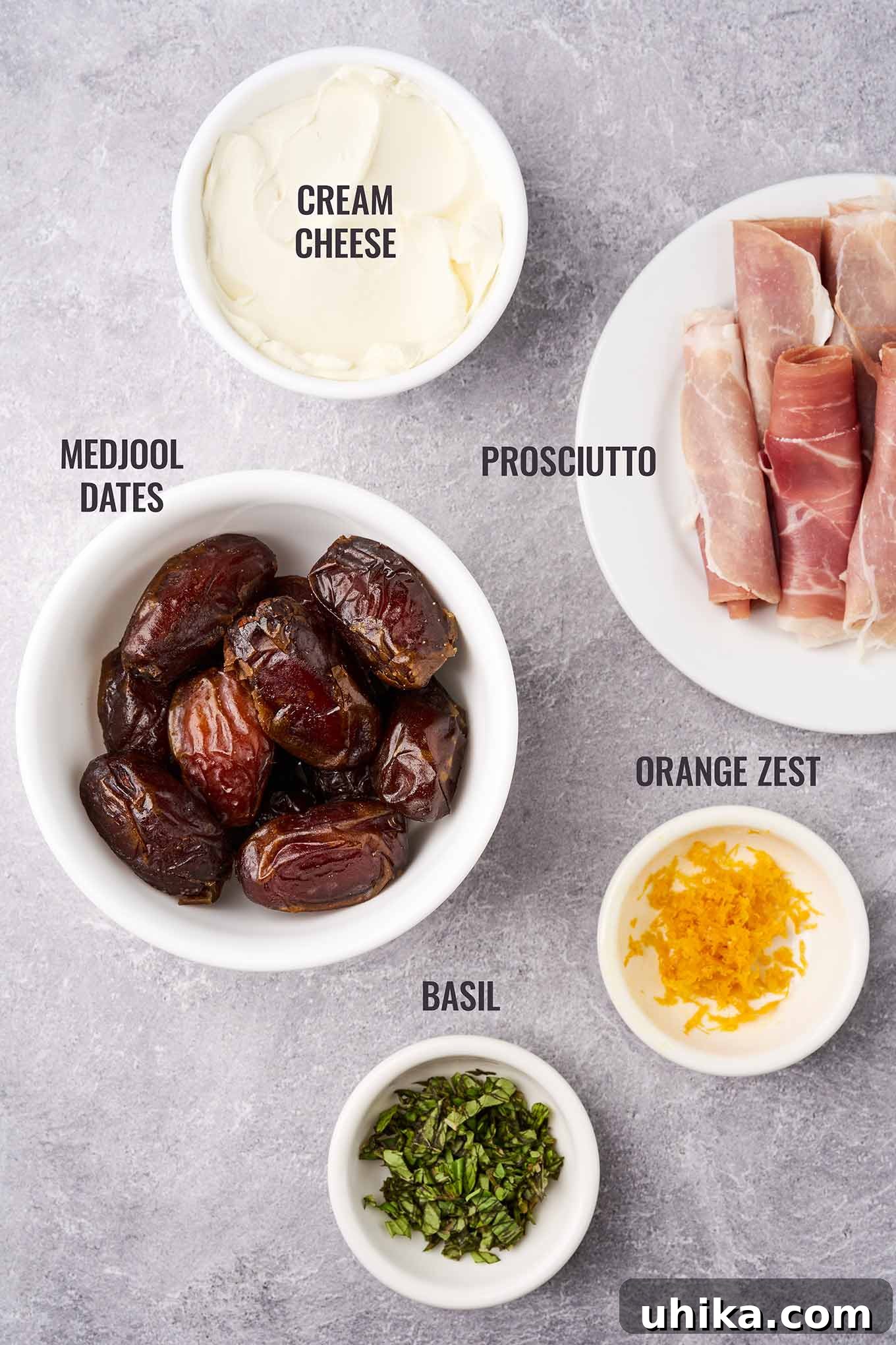 Sweet Salty Creamy Prosciutto Date Bites 3 A labeled, overhead view of the ingredients needed for stuffed dates including Medjool dates, prosciutto, cream cheese, fresh basil, and orange zest.