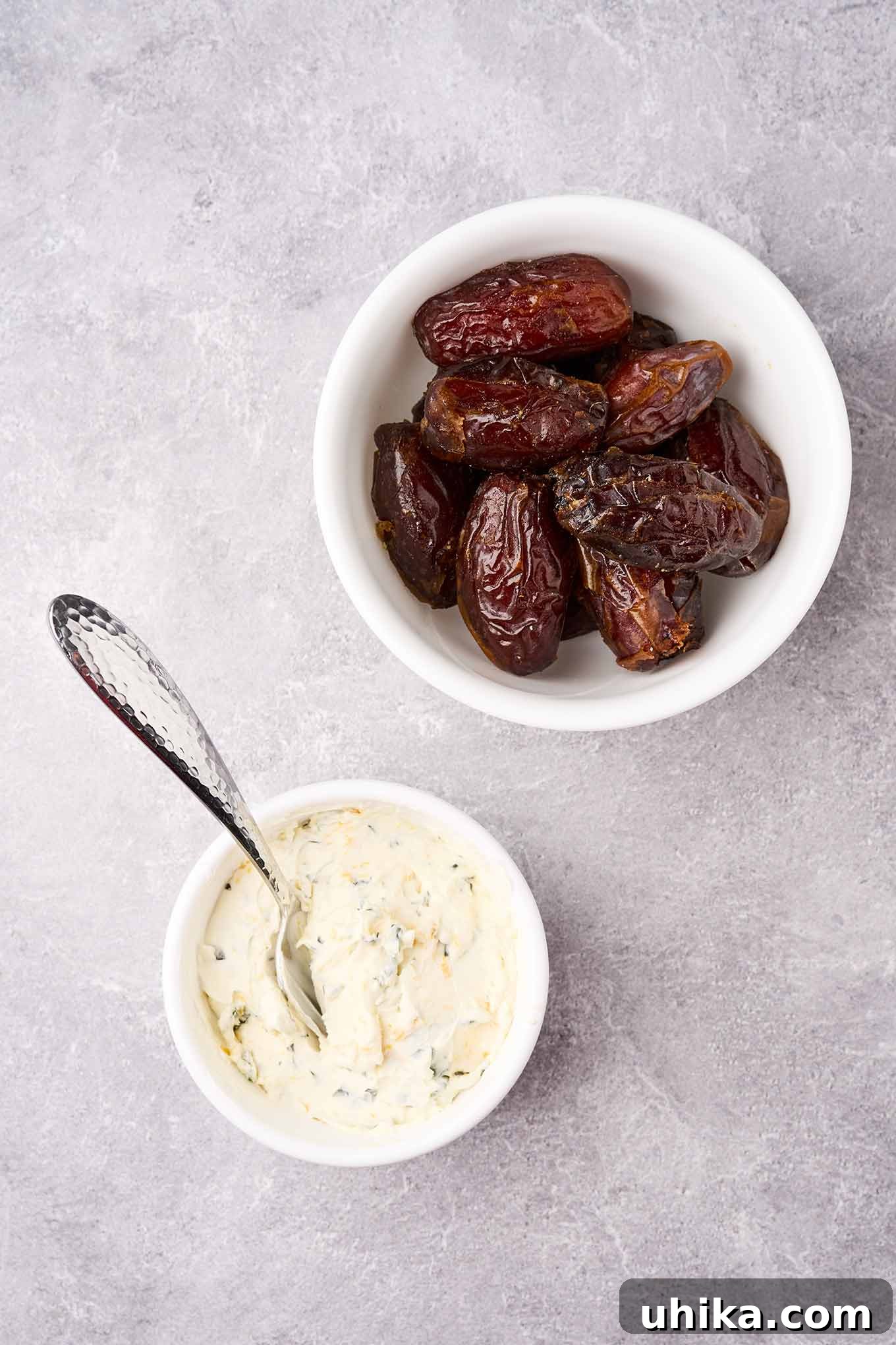 Sweet Salty Creamy Prosciutto Date Bites 4 A bowl of Medjool dates next to a bowl of cream cheese, basil, and orange zest filling, ready to make stuffed dates.