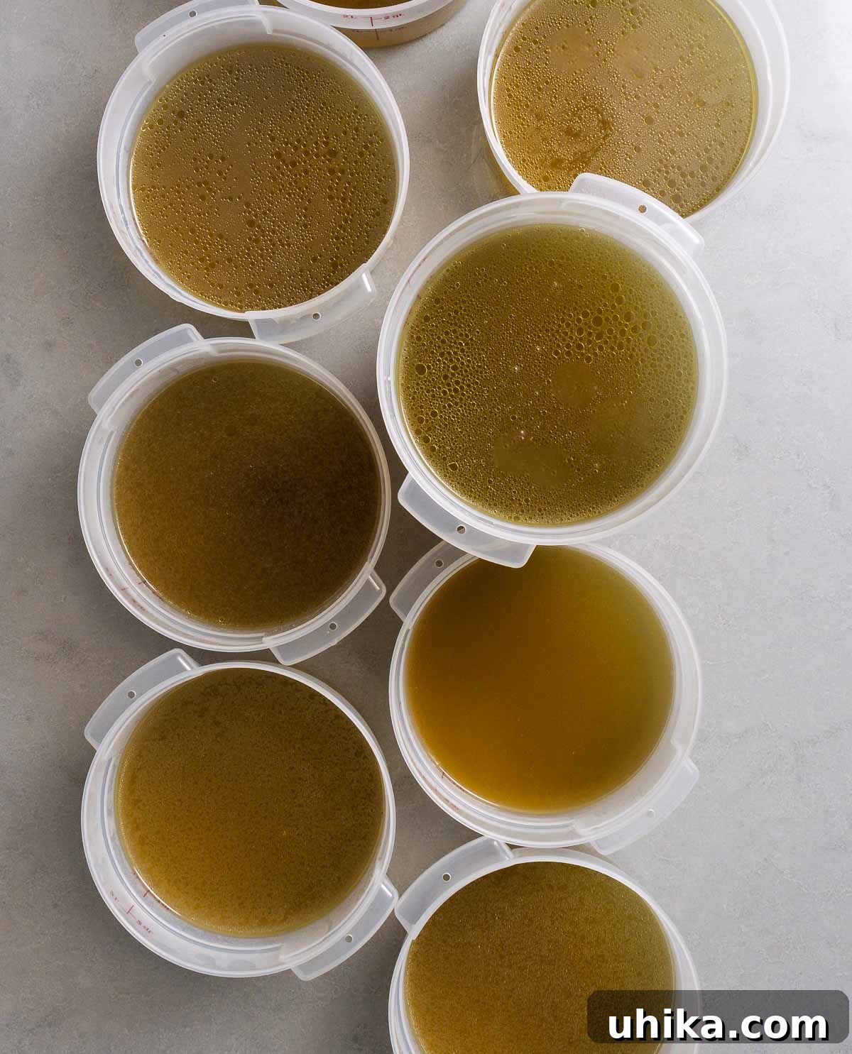 Homemade Liquid Gold 9 Multiple containers of homemade chicken stock on a granite countertop, ready for freezing or refrigeration.