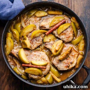 Featured image of a large black pan with perfectly cooked pork chops and tender apples in a rich sauce.