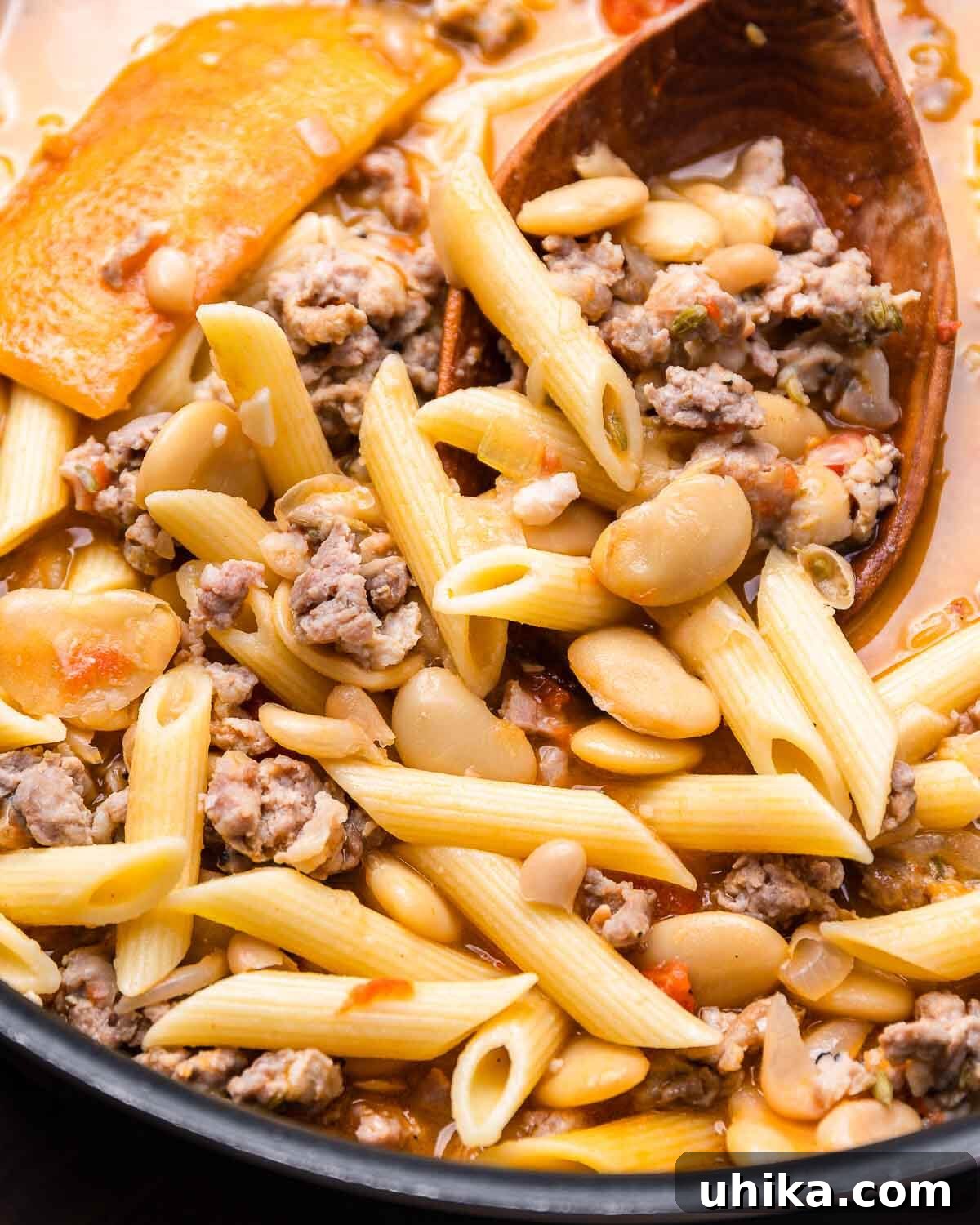 Pasta Fazool: The Dish, The Dialect, The Delight 6 Large wooden spoon scooping sausage pasta fagioli.