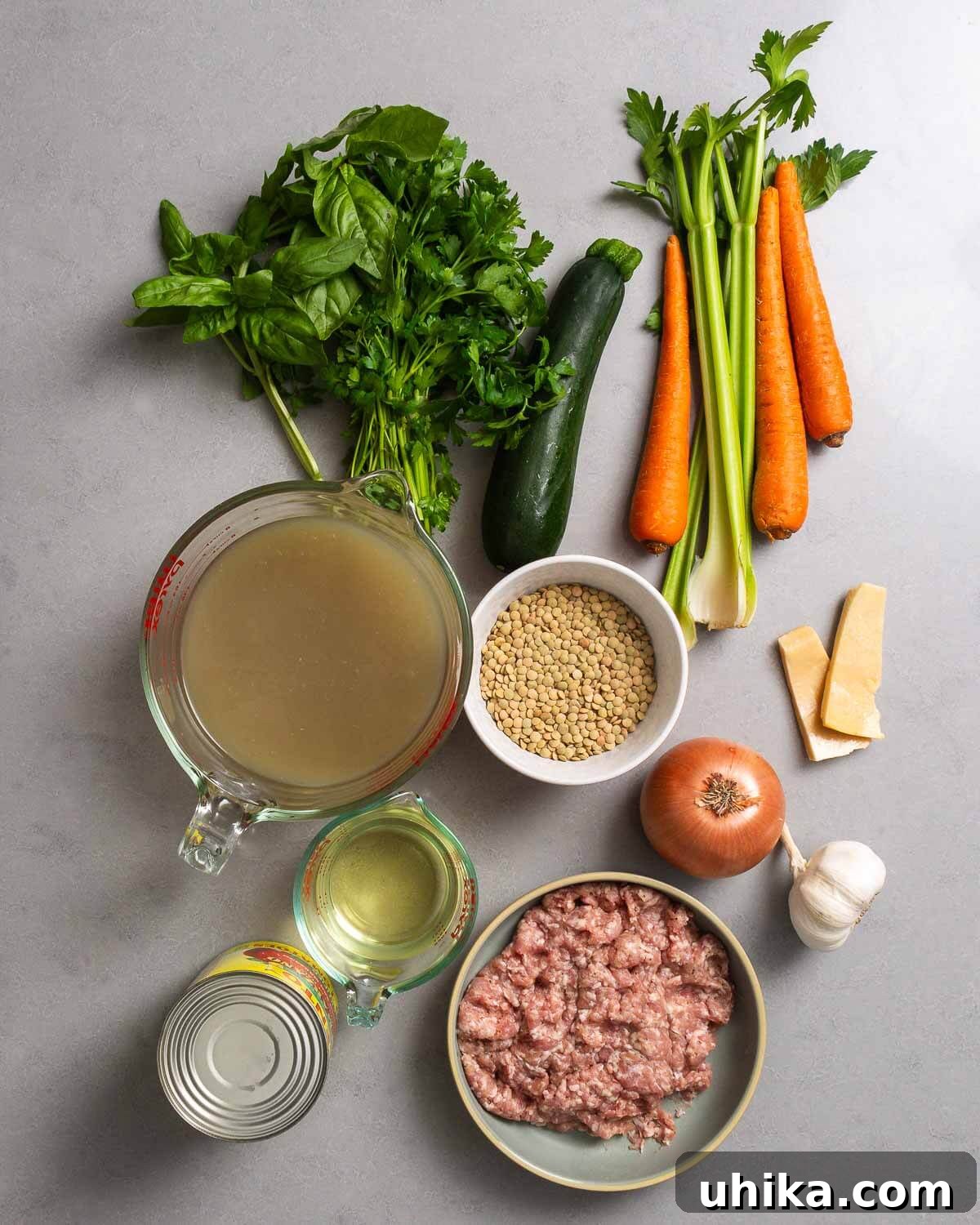 Rustic Sausage and Lentil Pot 3 Ingredients shown: herbs, zucchini, carrots, celery, chicken stock, lentils, onion, parmesan rinds, sausage, tomatoes, garlic, and dry whtie wine.