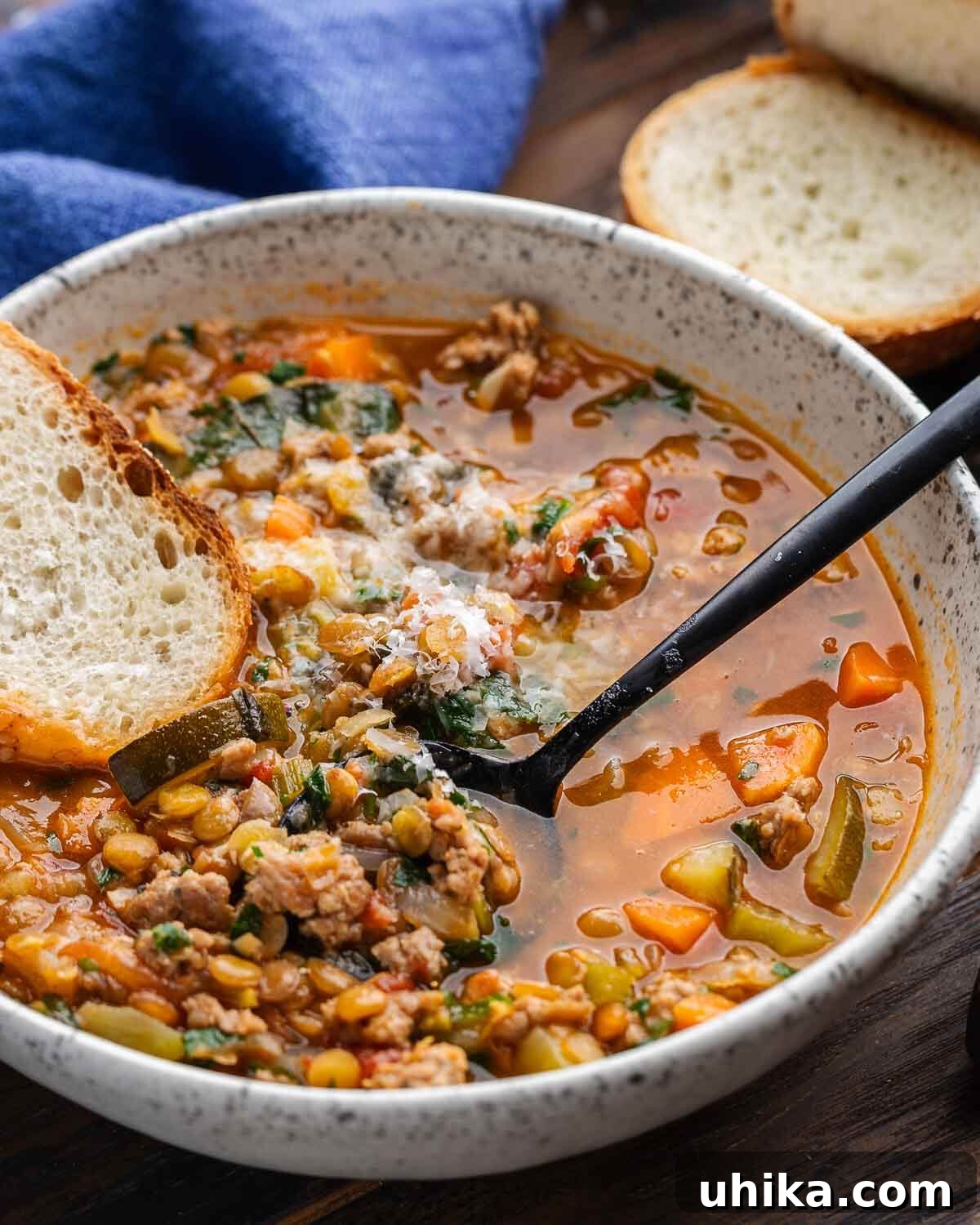 Rustic Sausage and Lentil Pot 8 Sausage lentil soup in white bowl with slice of bread and blue napkin in the background.
