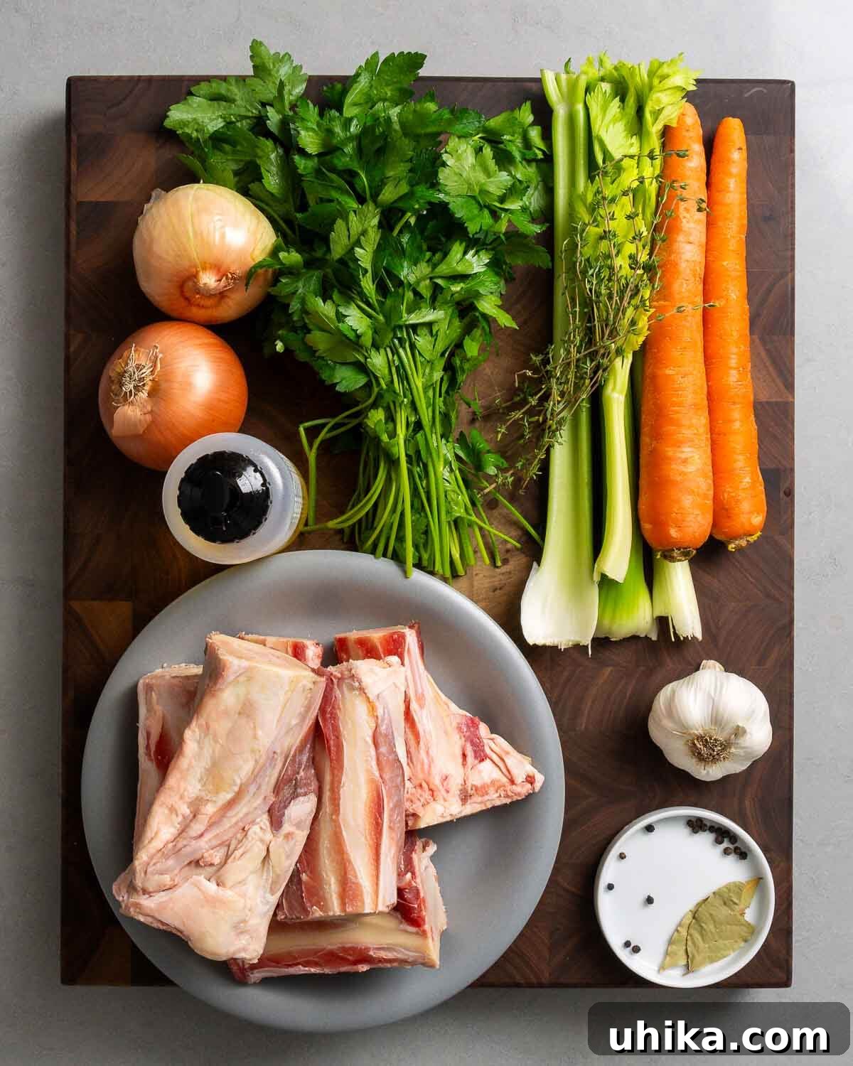 Liquid Gold Beef Stock 3 A vibrant display of ingredients for beef stock: robust beef bones, fresh onions, bright parsley, crisp celery, aromatic thyme, sweet carrots, rich olive oil, pungent garlic, whole peppercorns, and fragrant bay leaves.