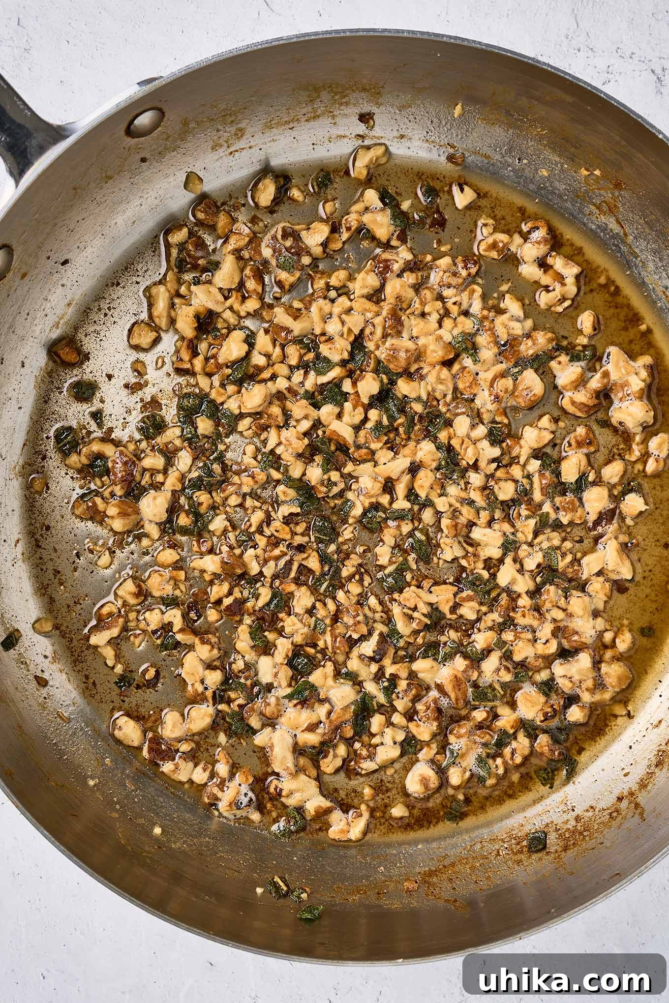 Nutty Brown Butter Chicken Pasta 6 The second step in preparing brown butter chicken pasta - sautéing chopped walnuts and fresh sage in brown butter. Perfectly browned milk solids are visible in the bottom of the pan.