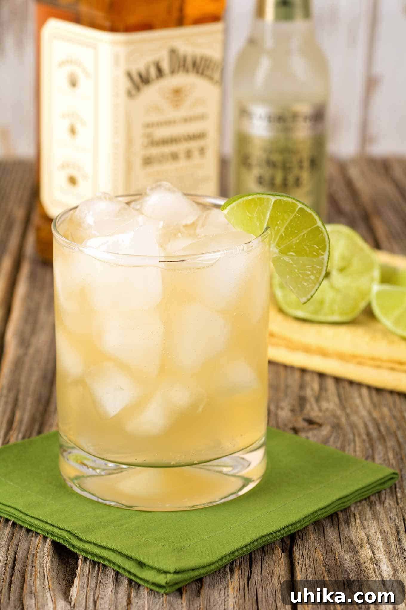 Golden Tennessee Honey Elixirs 2 A rocks glass filled with a cocktail of Jack Daniel's Tennessee Honey Whiskey combined with ginger beer and garnished with lime, bottles and sliced lime in the background.
