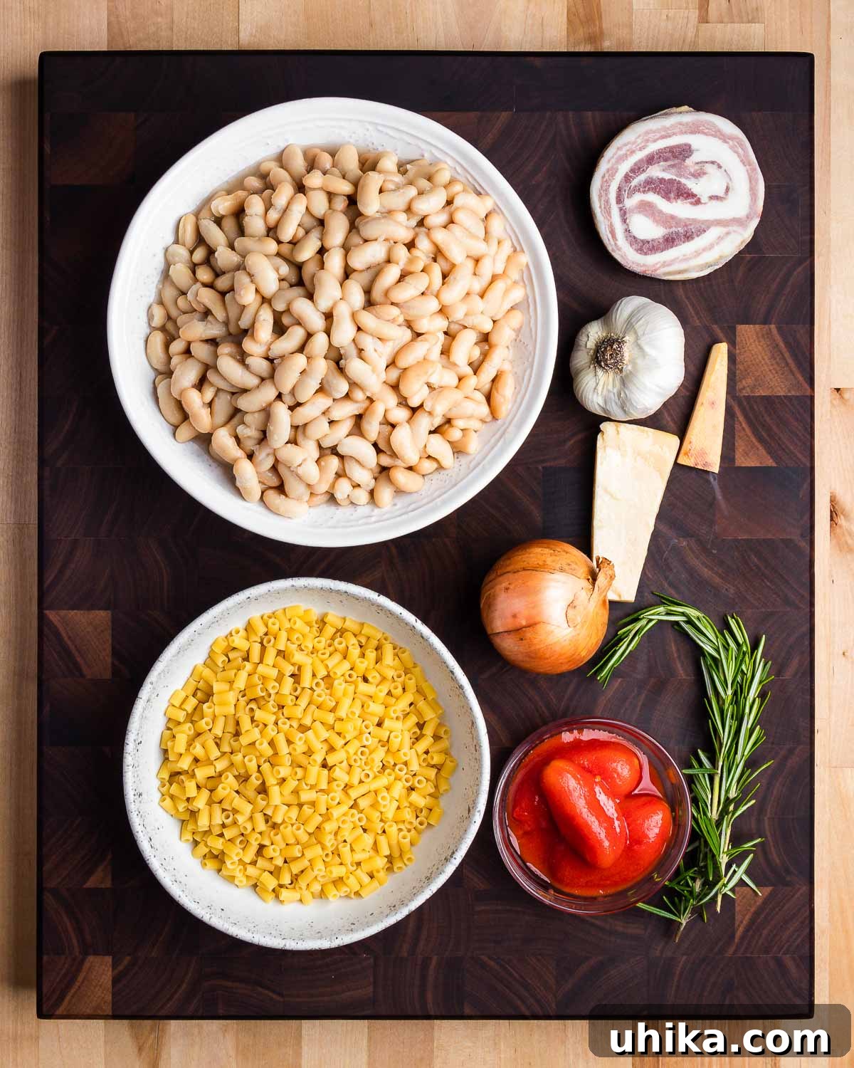 Pasta e Fagioli: Italy's Soul-Warming Classic 4 A detailed layout of all ingredients required for Pasta e Fagioli, including cannellini beans, diced pancetta, fresh garlic cloves, a whole onion, ditalini pasta, canned plum tomatoes, and a sprig of fresh rosemary.
