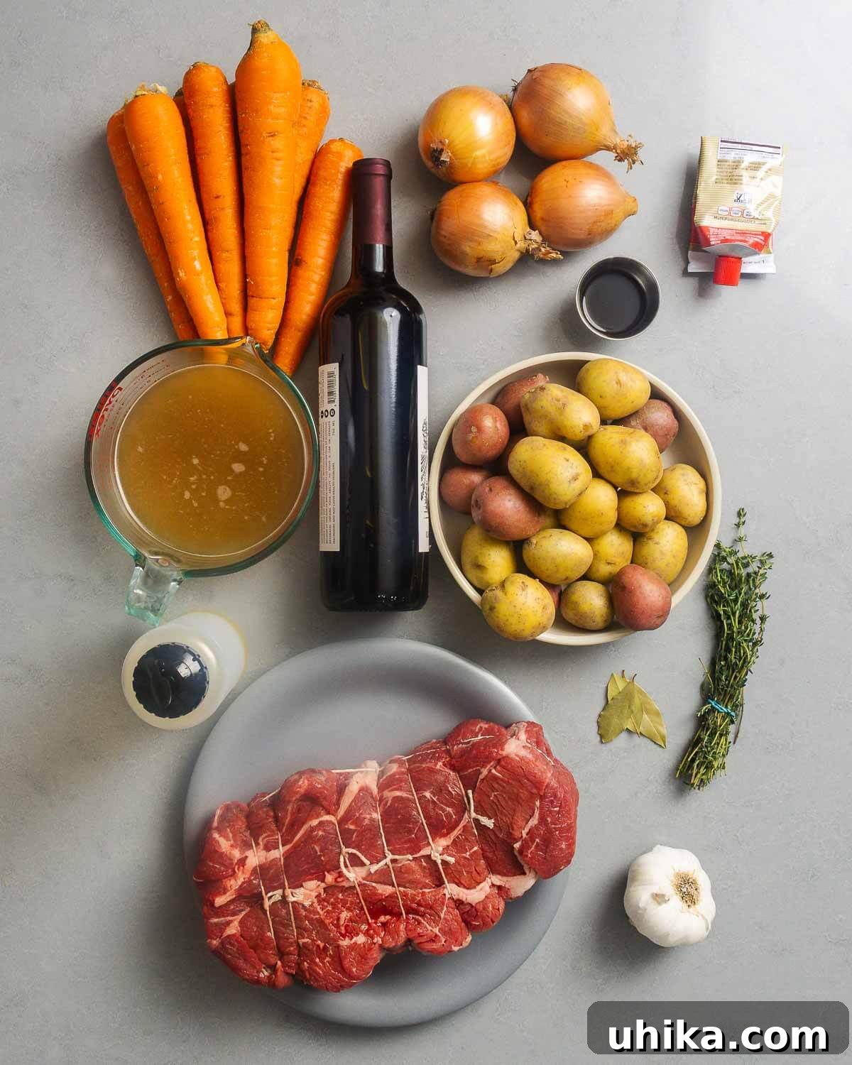 Fall-Apart Tender Beef 4 Ingredients shown: carrots, onions, red wine, worcestershire sauce, tomato paste, beef stock, potatoes, olive oil, thyme, bay leaves, chuck roast, and garlic.
