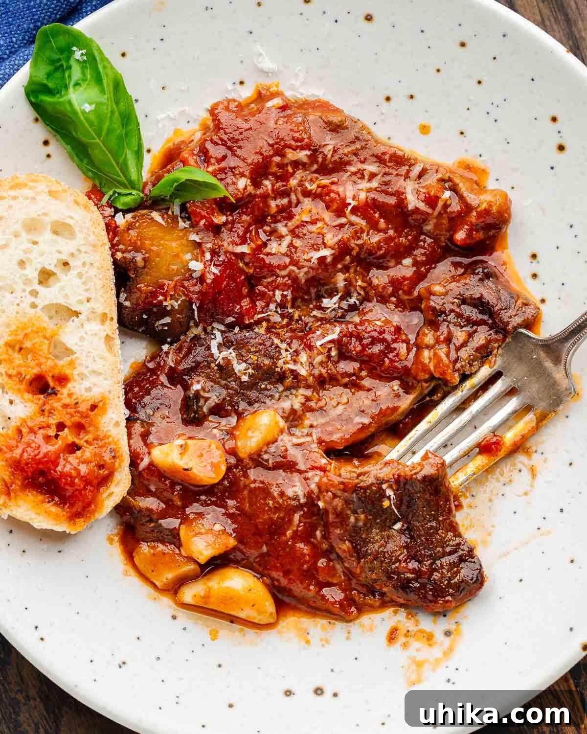 Podcast 20 Steak Pizzaiola The Ultimate Affordable Steak Dinner Hack 3 White plate with cut piece of steak pizzaiola and lots of garlic cloves.