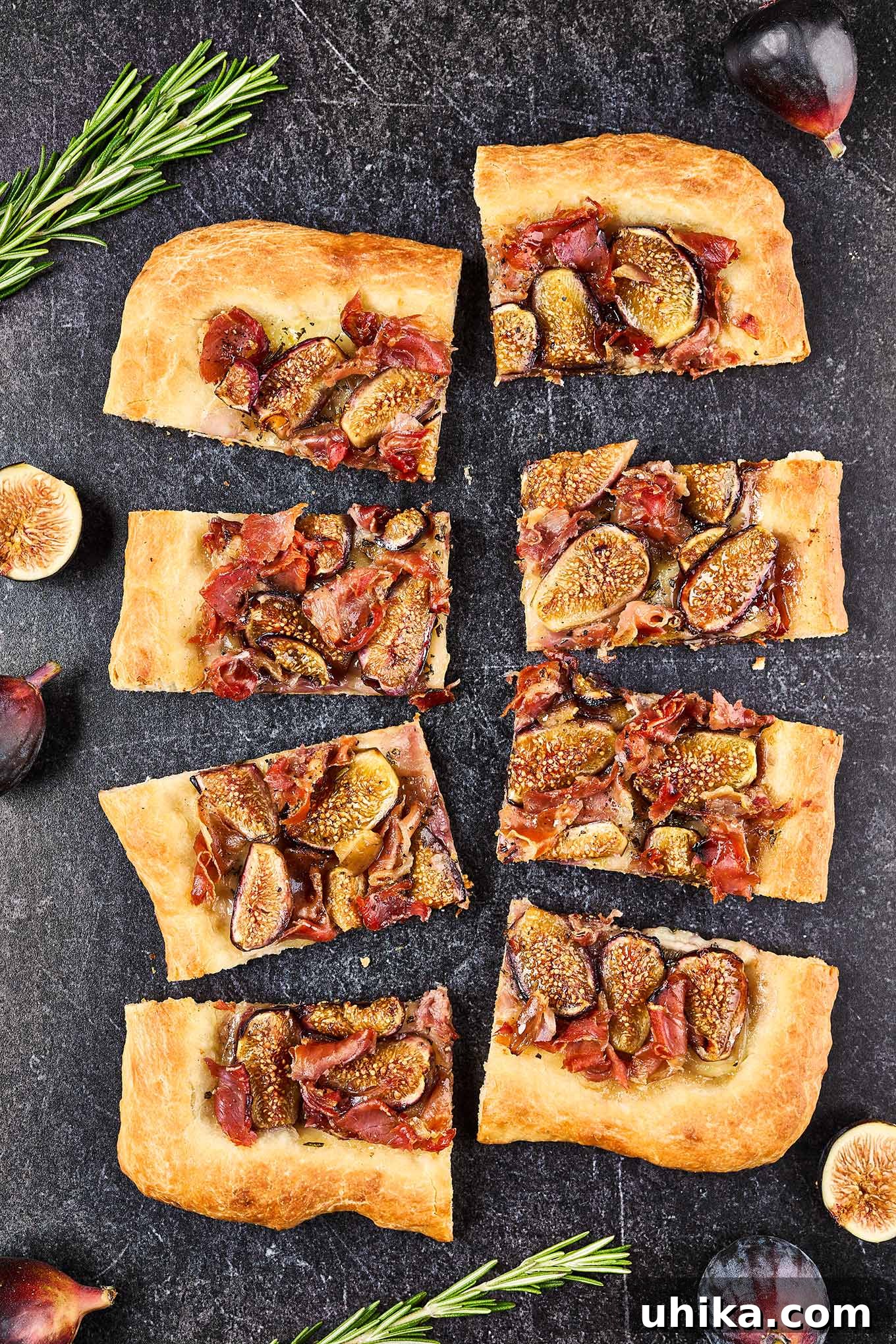 Gourmet Fig Prosciutto Brie Pizza 2 Slices of fig and prosciutto pizza on a slate background surrounded by fresh figs and sprigs of rosemary. A gourmet pizza with sweet figs, savory prosciutto, and creamy Brie.