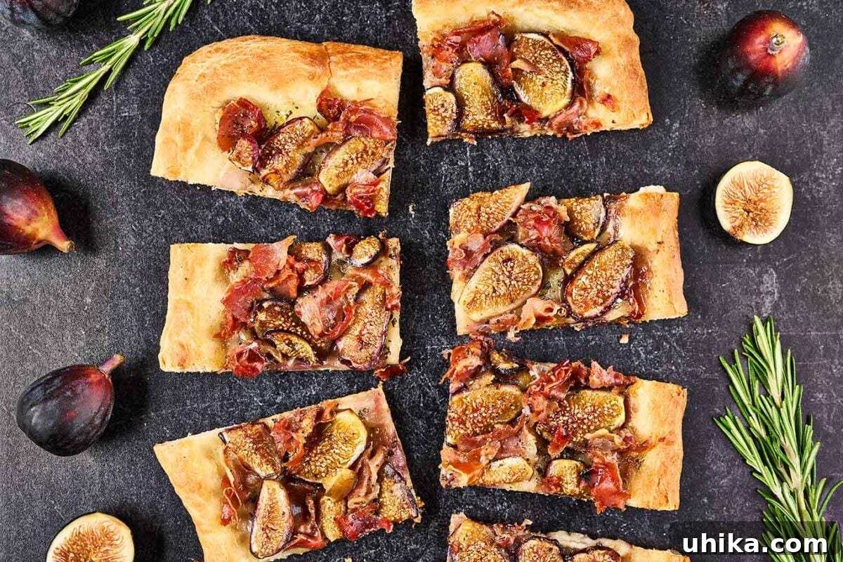 Gourmet Fig Prosciutto Brie Pizza 6 A rectangular fig and prosciutto pizza cut into appetizer-sized pieces, garnished with fresh figs and rosemary, ready for serving.