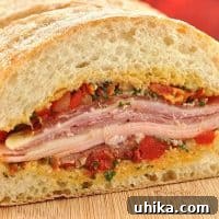 Close-up of a Mediterranean Muffuletta sandwich layered with cured meats, cheese, and olive tapenade on crusty ciabatta bread.