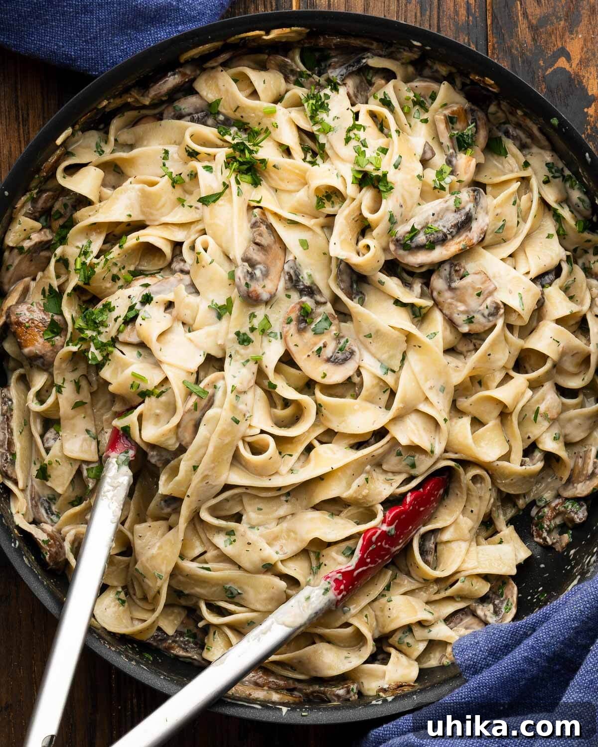 Luscious Garlic Mushroom Pasta 2 Creamy garlic mushroom pasta in a black pan, garnished with fresh parsley.