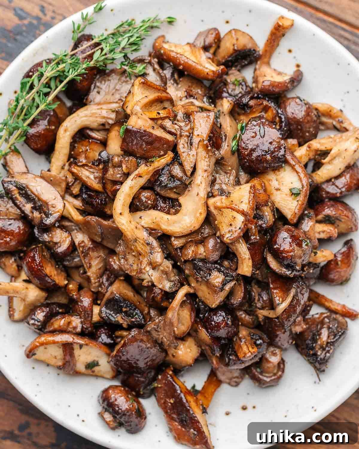 Golden Roasted Mushrooms 2 Roasted mushrooms with thyme garnish in white plate.